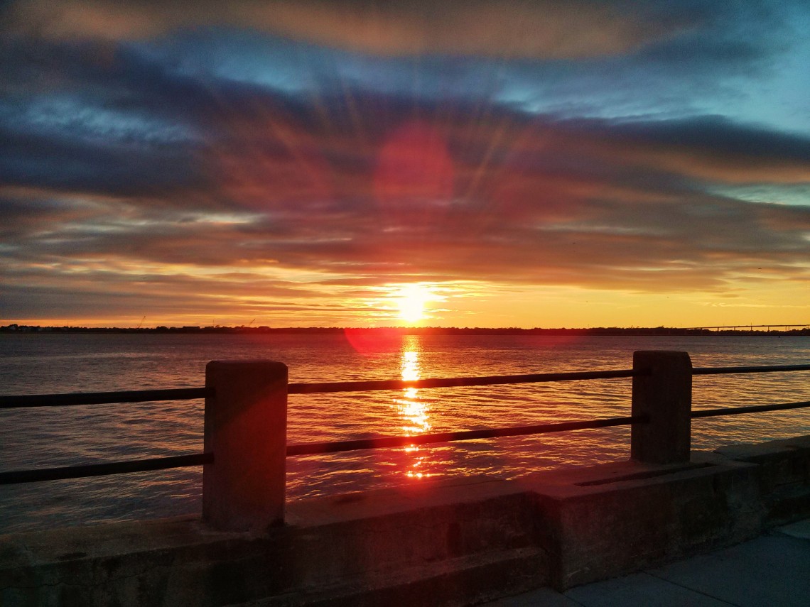 The sun setting with a spray of rays along the Ashley River in Charleston, SC