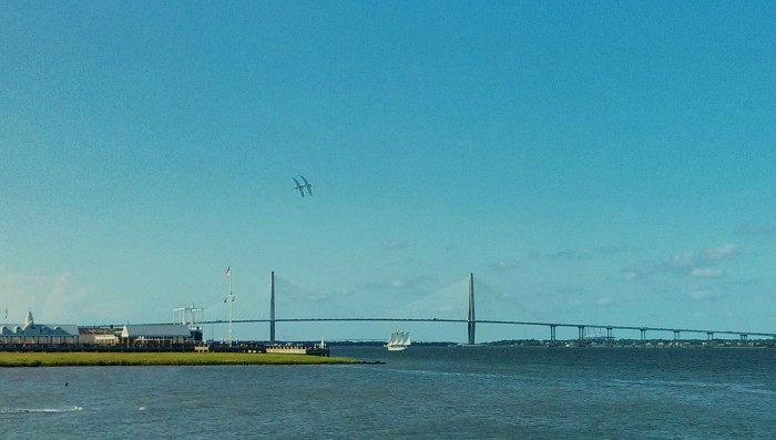 An amazing bridge, an historic aircraft carrier, a tall-masted schooner and pelicans soaring over it all = Charleston Harbor.