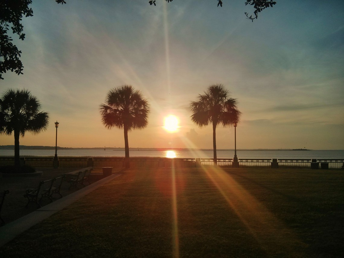 The sun rising over Charleston Harbor and Castle Pinckney, as seen from Waterfront Park.