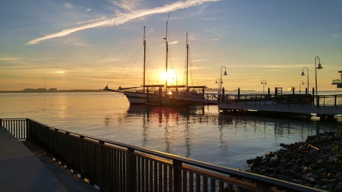 The sun rises over Charleston Harbor, lighting up the three-masted Schooner Pride.
