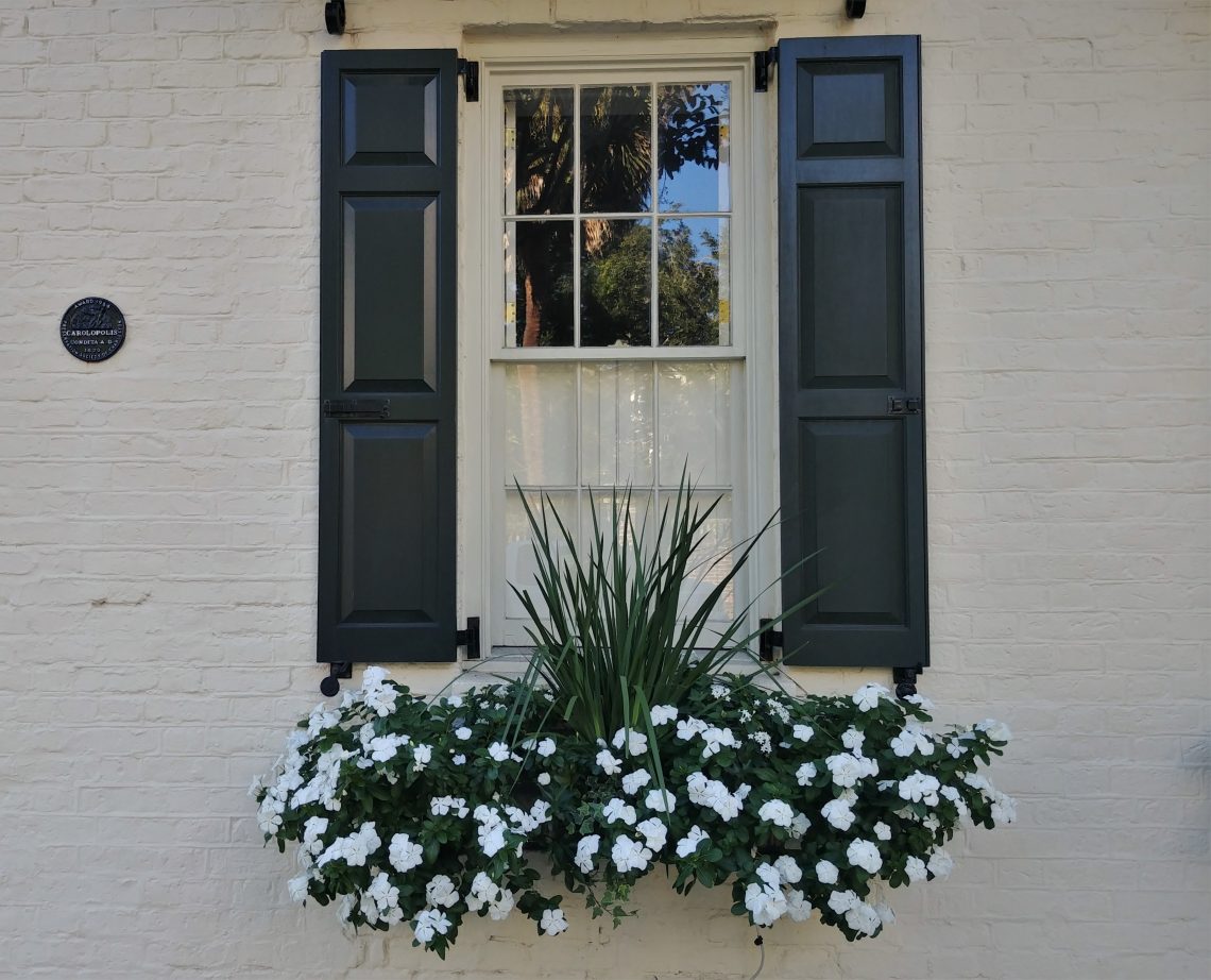 Eye-catching beauty, from small to big, can be found all over Charleston. While this flower box and window may represent a smaller amount, the black disk on the wall indicates something larger. The Carolopolis Award, as represented by the disk, has been bestowed for over 63 years by the Preservation Society of Charleston on properties that have achieved excellence in historic preservation. Look around the city and you will find over 1400 of these symbols.