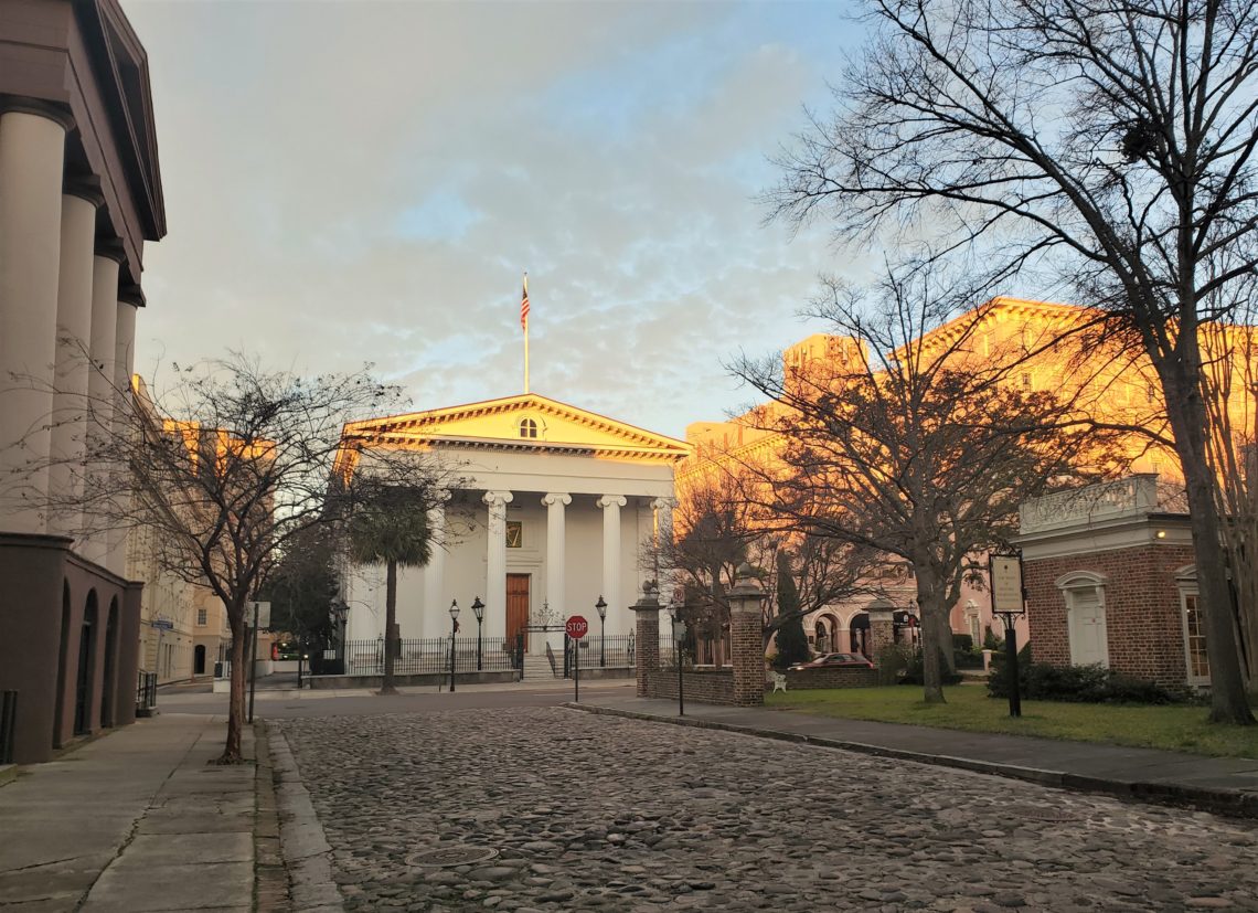 The first rays of the sun lighting up the top of Hibernian Hall on Meeting Street. Built in 1840, the beautiful Greek Revival building is fronted by iron gates created by the master artisan Christopher Werner.